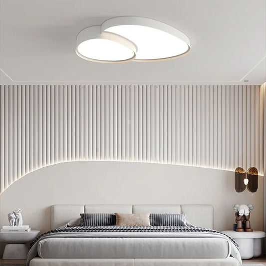 White cloud-shaped LED semi-flush mount ceiling light above a bed in a contemporary bedroom setting.