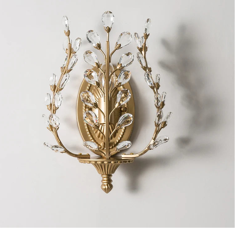 Decorative wall sconce with gold and crystal design on a light gray background.