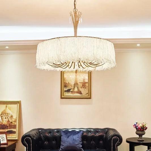Gold crystal waterfall chandelier hanging above a black tufted sofa with artwork on the wall.
