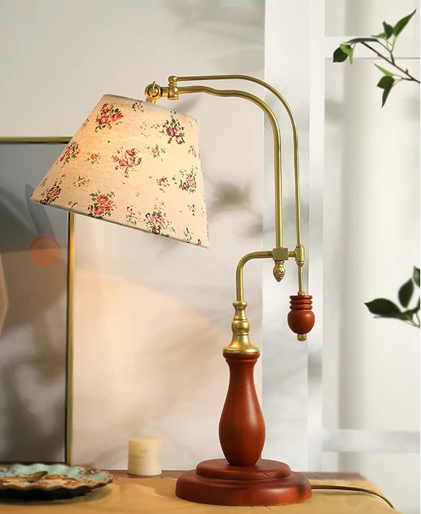 Vintage-style table lamp with floral shade on a wooden surface.