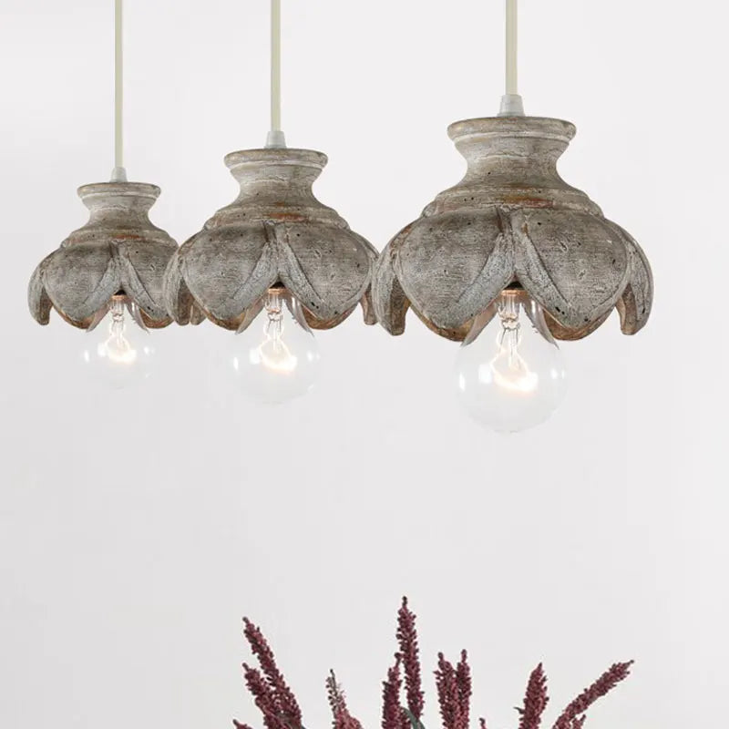 Three wood carved floral pendant lights with distressed finishes arranged together.
