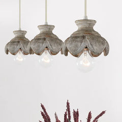Three wood carved floral pendant lights with distressed finishes arranged together.