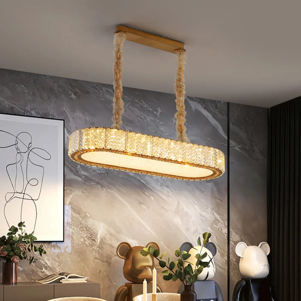 Oval shaped gold chandelier with clear crystals hanging from the ceiling, showcasing a modern design.
