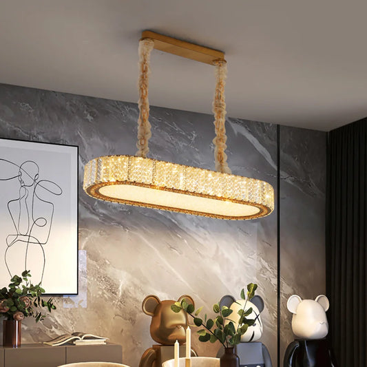 Oval shaped gold chandelier with clear crystals hanging from the ceiling, showcasing a modern design.