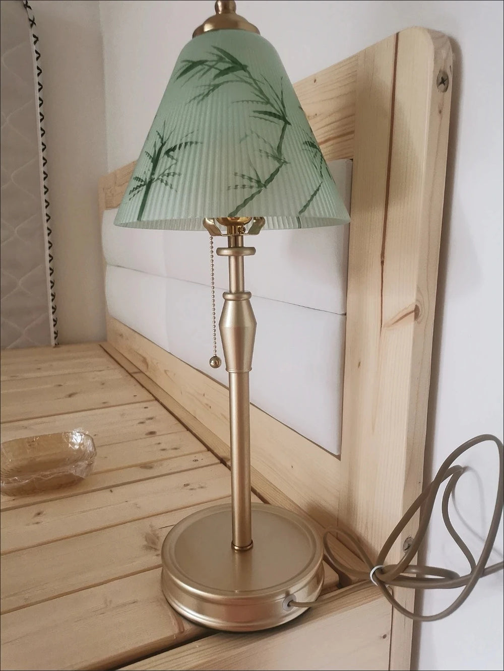 Table lamp with a green floral-patterned shade on a wooden surface.