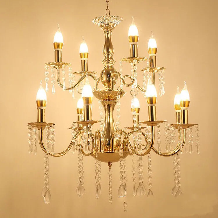 A grand, multi-tiered gold chandelier with candelabra-style arms adorned with cascading clear crystals, illuminated with warm white LED bulbs against a cream background.