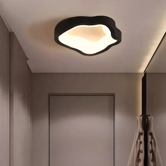 Black wavy-shaped ceiling light mounted on a neutral ceiling in a hallway
