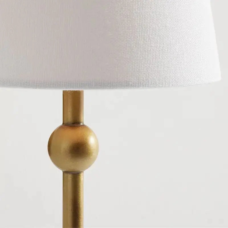 Lamp with a gold base and white shade on a light gray background