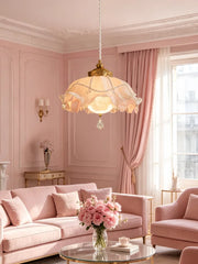Pink floral lampshade with crystal accents hanging in a pink living room with a velvet sofa.