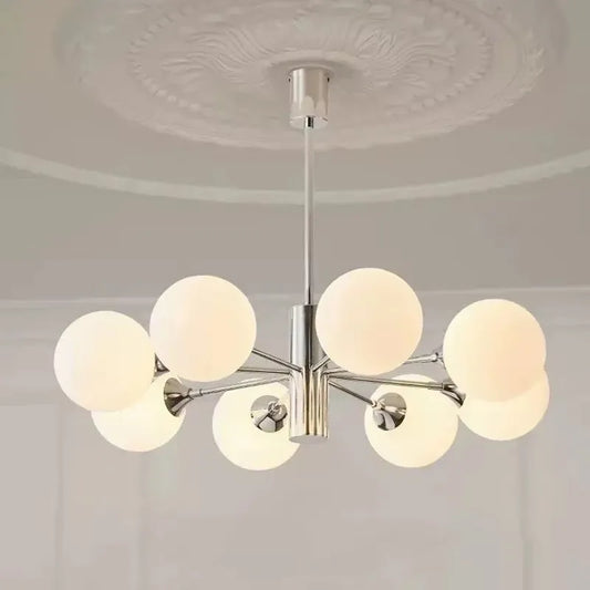 Close-up of a polished chrome sputnik chandelier with multiple frosted opal glass globes mounted on radiating arms, shown against a white ceiling with decorative molding.