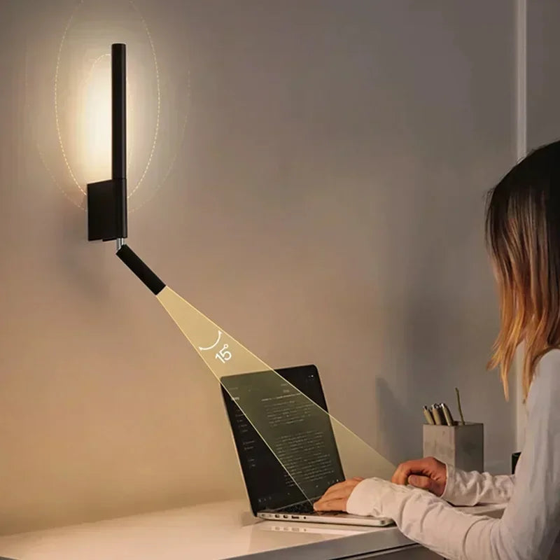 A person using a laptop, illuminated by a black adjustable LED wall sconce demonstrating the 15-degree angle.