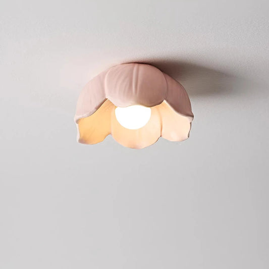 Close-up of a pink ceramic flower-shaped semi-flush ceiling light with a frosted finish, illuminated by an internal LED bulb.