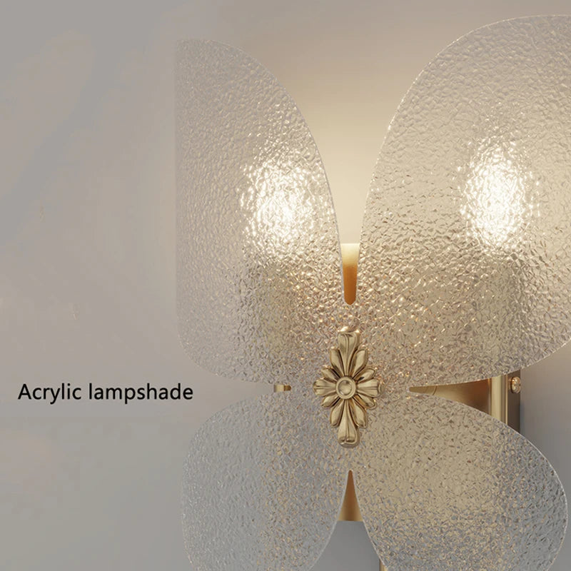 Wall-mounted light fixture with acrylic lampshades and decorative element on a plain background