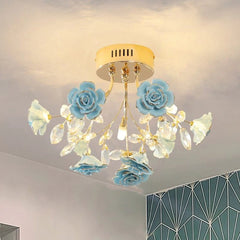 A flush mount ceiling light with a gold base and blue ceramic roses, illuminated against a ceiling.