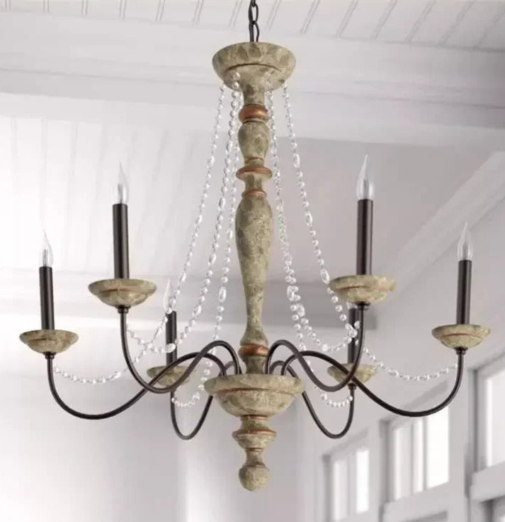 Vintage-style chandelier with wooden design and candle-like lights in a room with white walls.