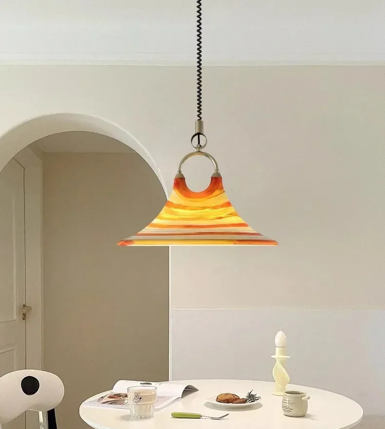 Modern dining area with a round table, chairs, and a colorful pendant light.