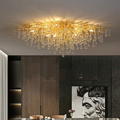 A large, gold crystal chandelier with a branch-like design and teardrop crystals hanging above a dining table.