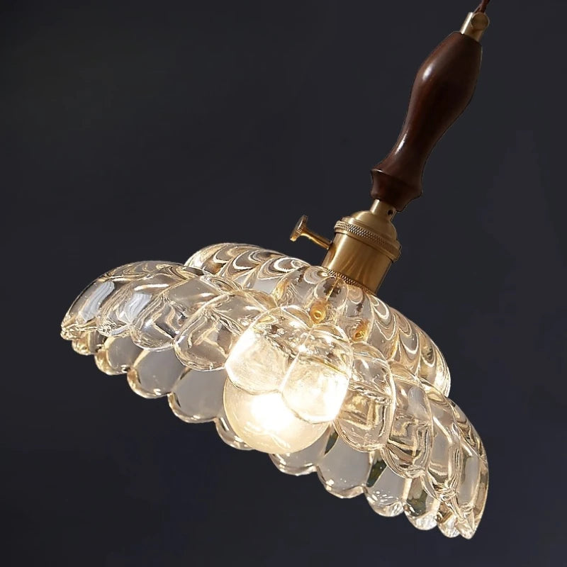 Vintage-style pendant light with clear glass shade and wooden fixture on a dark background