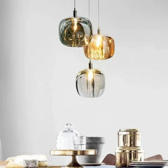 Close-up of three hanging crystal ball pendant lights in smoke gray, amber, and clear, over a table setting.