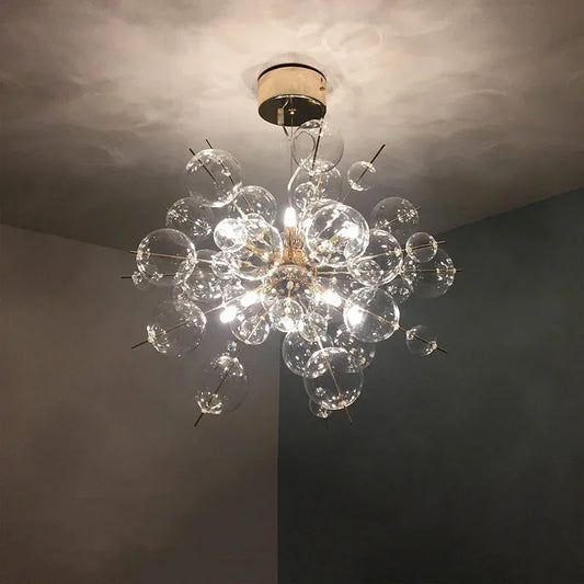 Close-up of a gold-toned starburst chandelier featuring numerous clear glass orbs of varying sizes, showcasing the warm LED illumination.