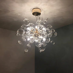 Close-up of a gold-toned starburst chandelier featuring numerous clear glass orbs of varying sizes, showcasing the warm LED illumination.