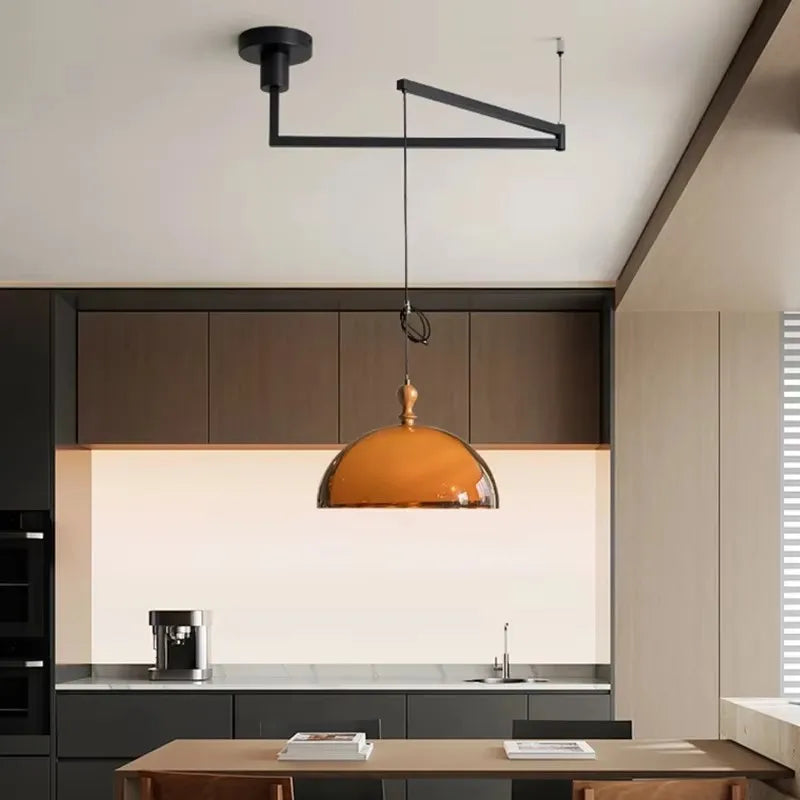Kitchen island pendant light with an amber glass dome shade and black adjustable arm