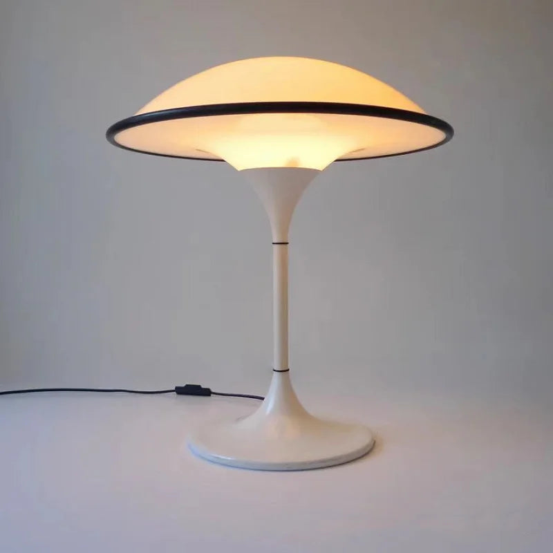 Modern table lamp with a white base and yellowish light on a plain background