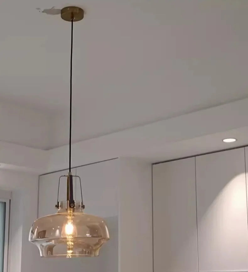 Pendant light with glass shade hanging in a room with white walls and ceiling.