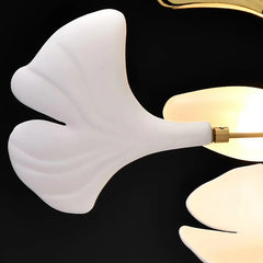 Gold ginkgo leaf cluster pendant light hanging in a white, minimalist room with a sofa