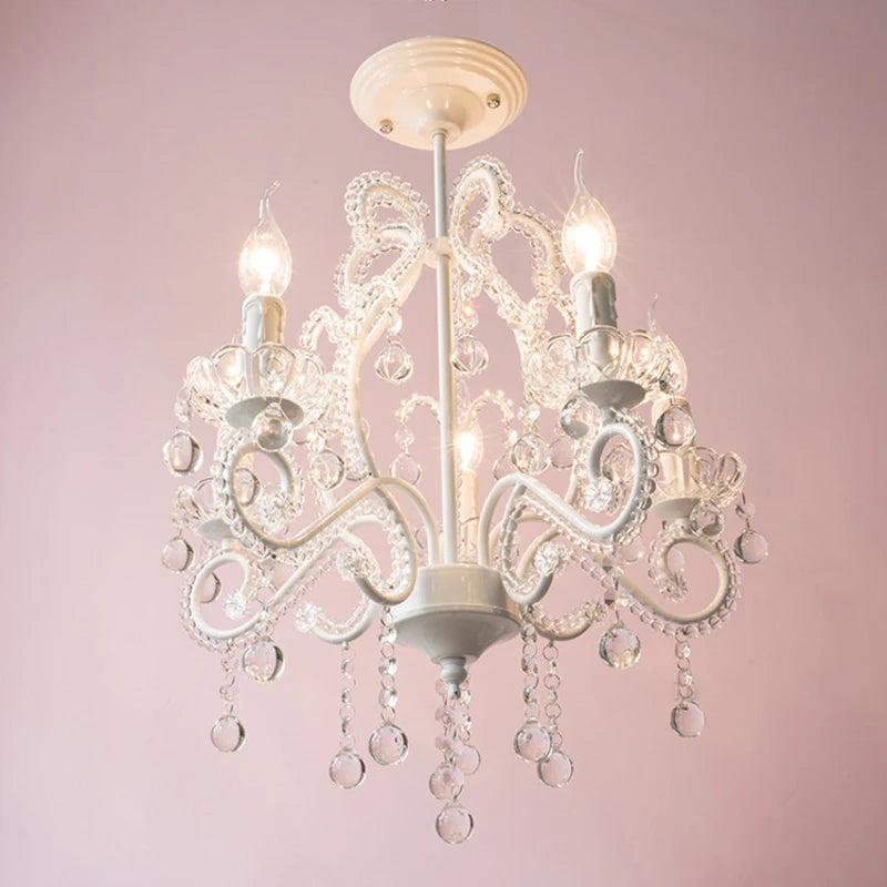 Close-up of the top section of a white chandelier with a bow-like design and crystal embellishments.