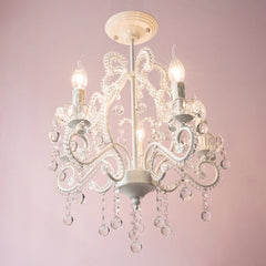 Close-up of the top section of a white chandelier with a bow-like design and crystal embellishments.