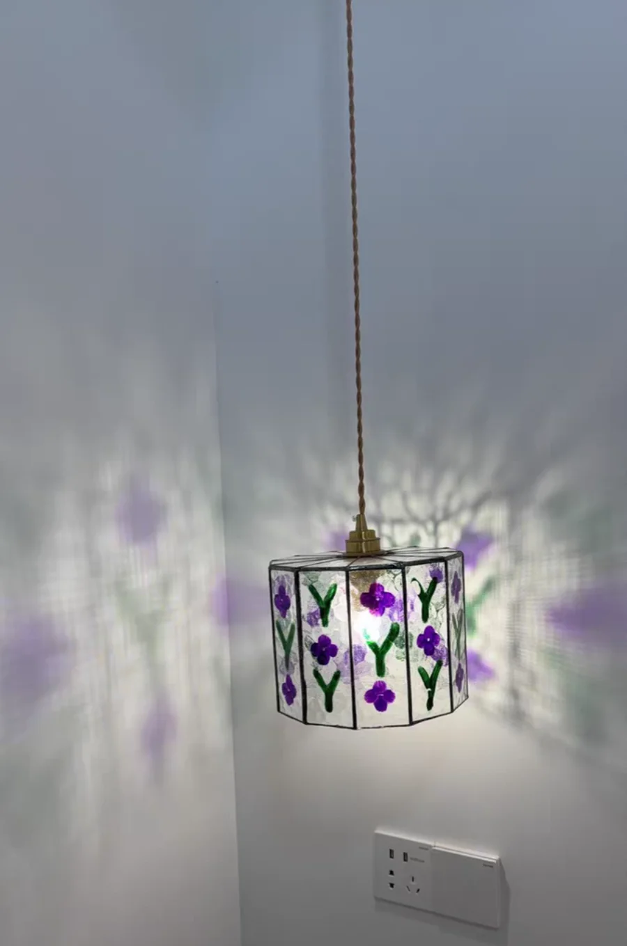 Decorative pendant light with floral design on a white wall.
