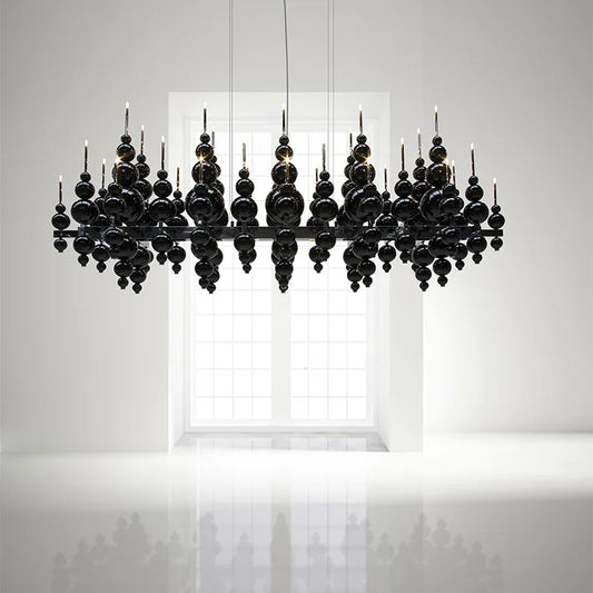 Black globe cluster pendant light against a white wall with a window in the background, showing a reflective surface below.
