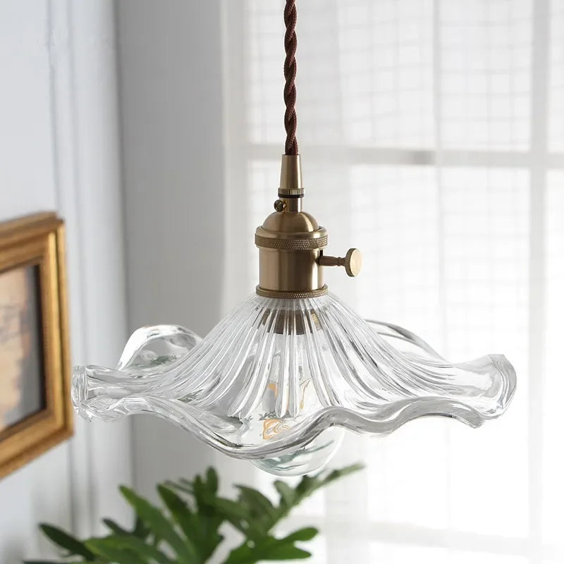 Vintage-style pendant light with clear glass shade and brass fixture in a room setting.