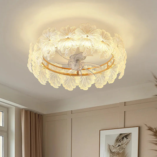 Gold-finished circular ceiling light fixture with many clear glass flower petals arranged around the outer edge, with a central fan and frosted glass diffuser.