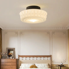 White frosted glass drum semi-flush ceiling light above a bed in a bedroom.