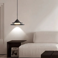 Close-up view of the matte black tiered pendant light with glowing frosted glass diffuser.
