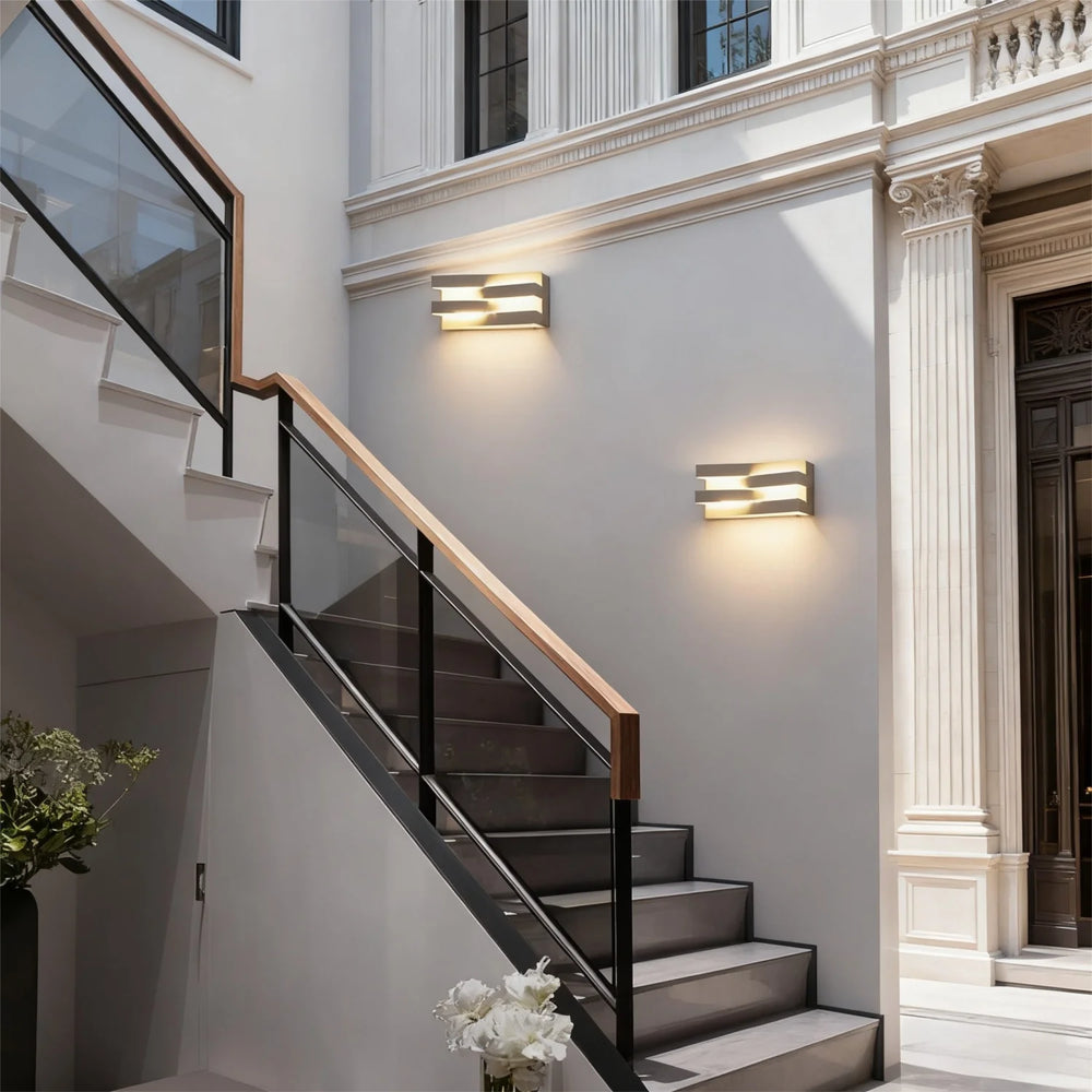 Staircase with modern railings and wall lights in a well-lit interior setting.