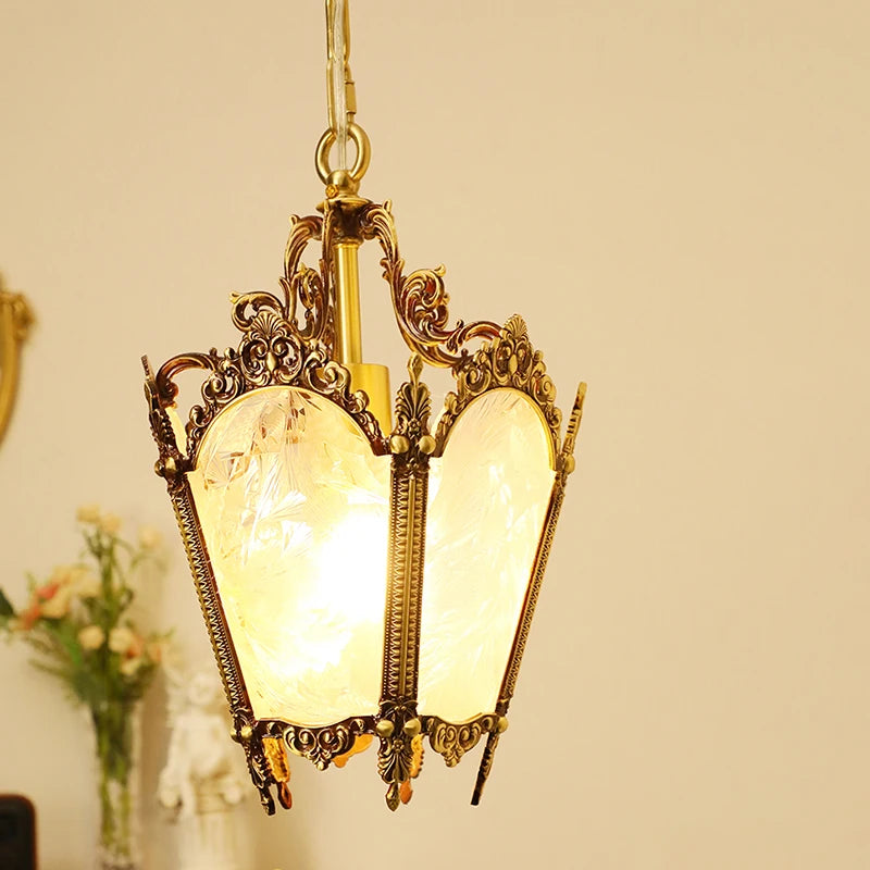 The polished copper floral glass pendant light is shown in a softly lit interior, with a hint of flowers in the background.