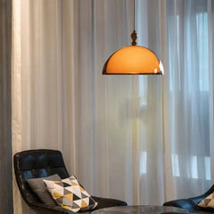 Close-up of an amber glass dome pendant light with wooden accent