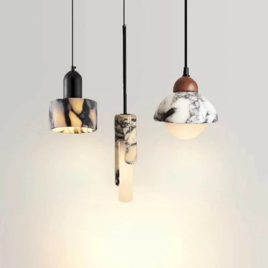Three marble and wood pendant lights with frosted glass shades hanging against a light background, showcasing their unique designs.