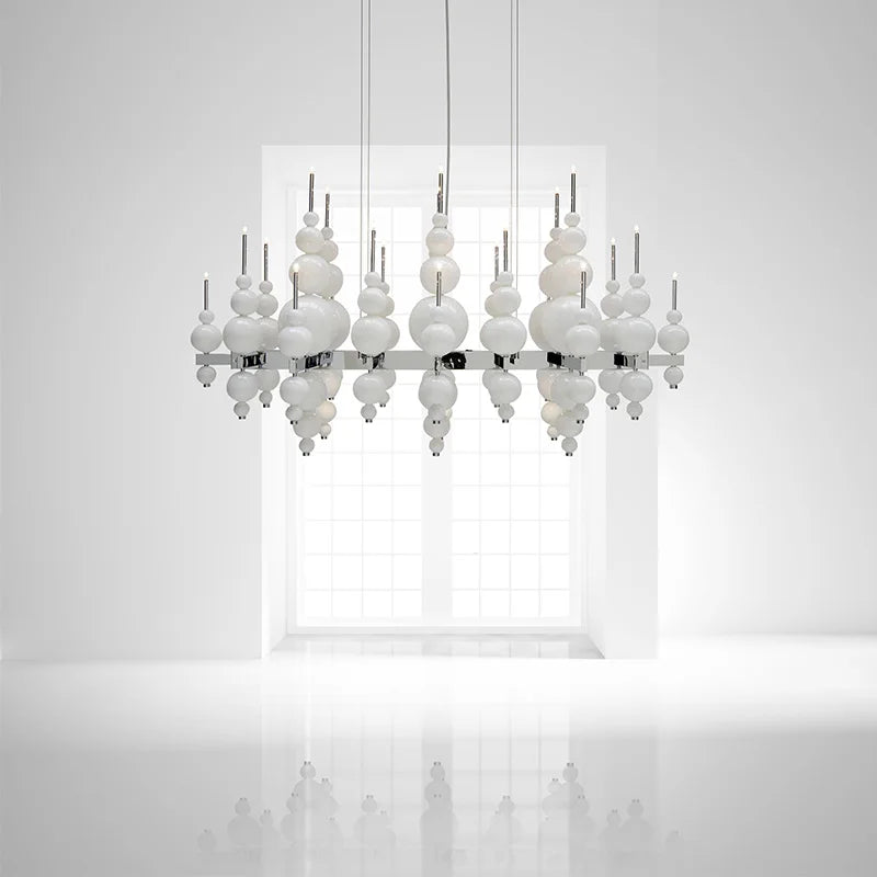 White globe cluster pendant light against a white wall with a window in the background, showing a reflective surface below.