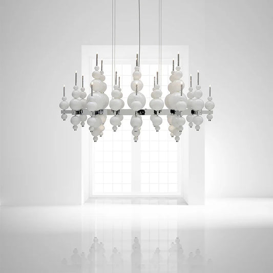 White globe cluster pendant light against a white wall with a window in the background, showing a reflective surface below.