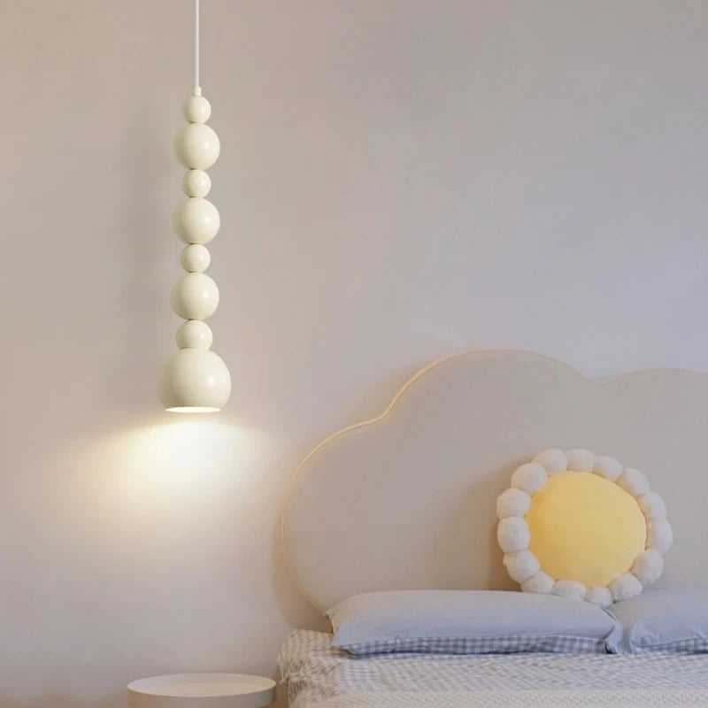 Cream gourd-shaped pendant light hanging in a bedroom next to a cloud-shaped headboard.
