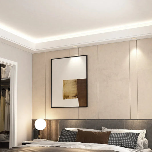 A modern bedroom with subtle recessed ceiling lights illuminating the wall and bed area.
