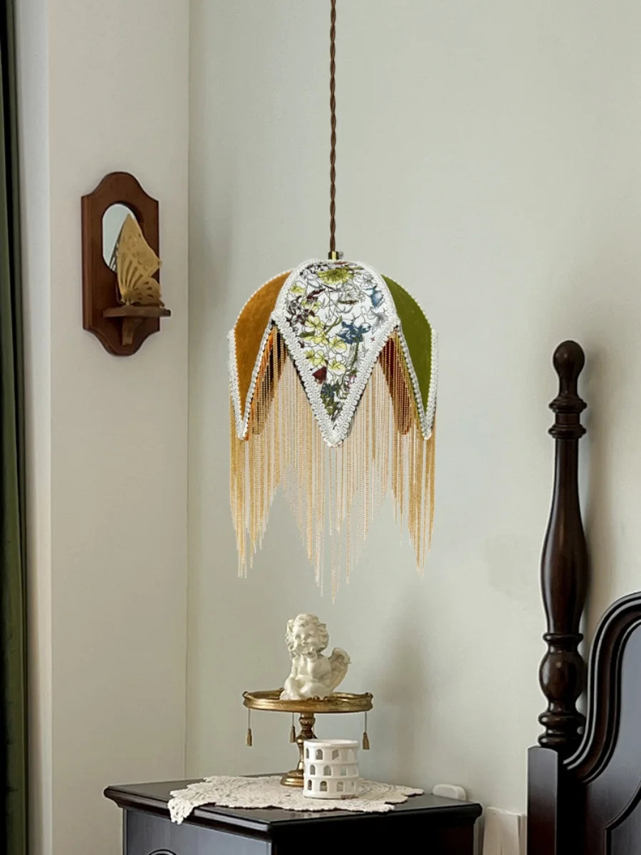 Decorative wall hanging with fringes and a small statue on a shelf against a light green wall.