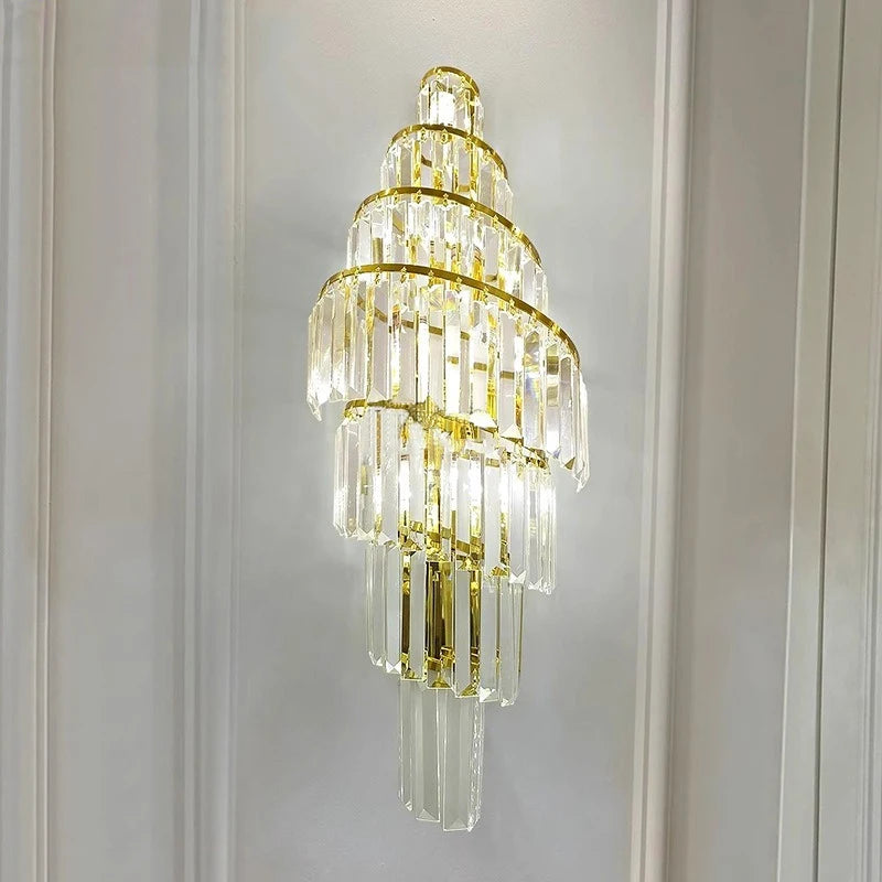 A gold crystal spiral wall sconce mounted on a wall with vertical paneling, highlighting its elegant and decorative form.