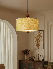 Green floral fabric drum pendant light with wood accents hanging in a room