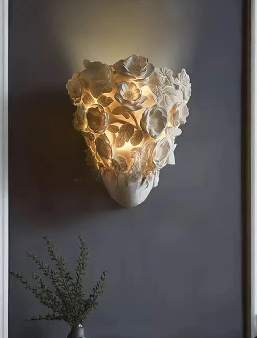 Decorative wall light fixture in a modern interior setting with a dark gray wall and a vase with greenery.