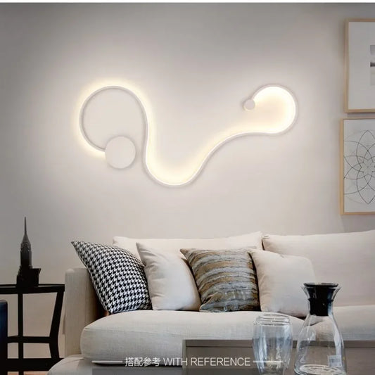 White wave-shaped LED wall sconce with cool light mounted on a white wall above a light-colored sofa.